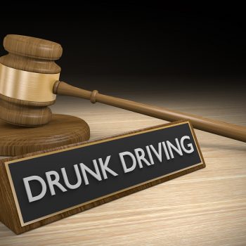 DUI law concept of a wooden court gavel lying next to a sign that reads Drunk Driving.