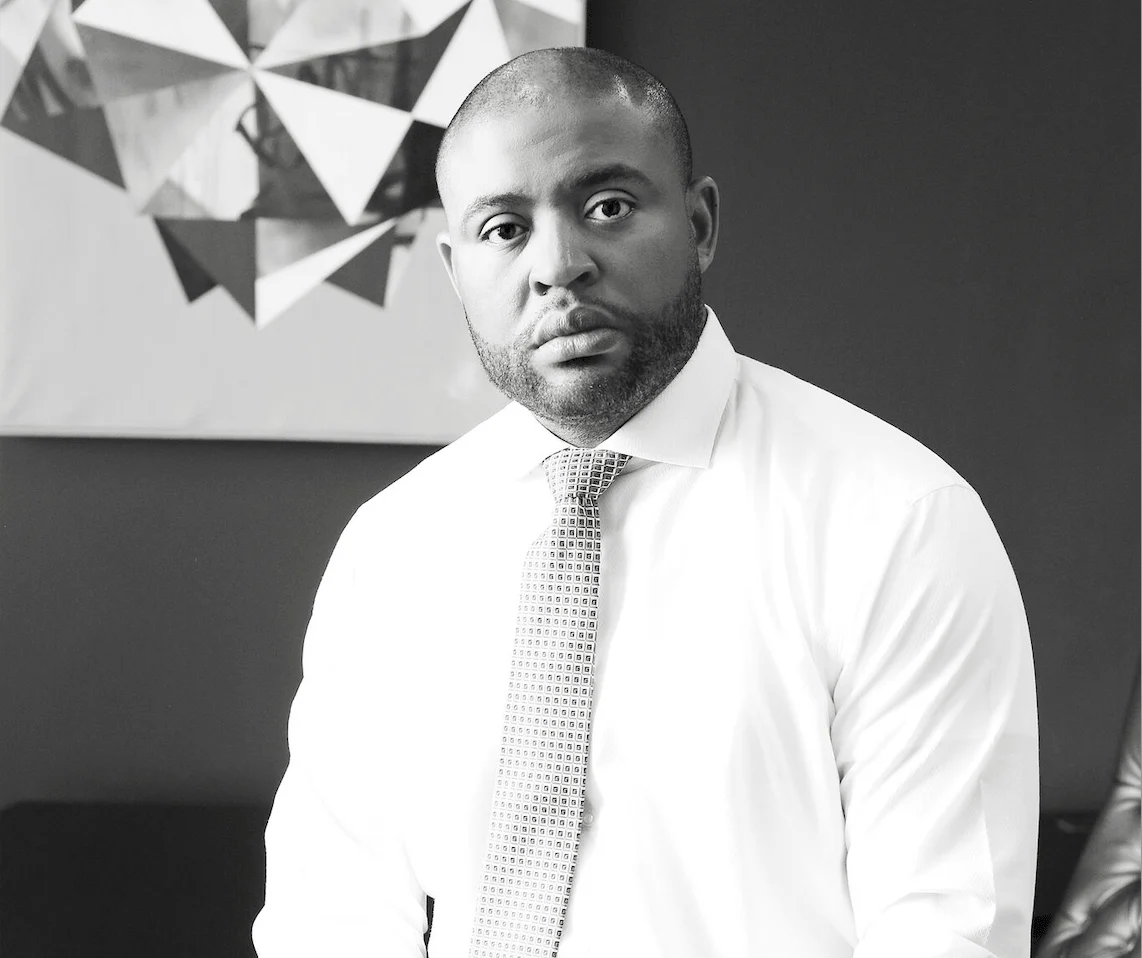 a black and white portrait of attorney brandon brown wearing a shirt and tie